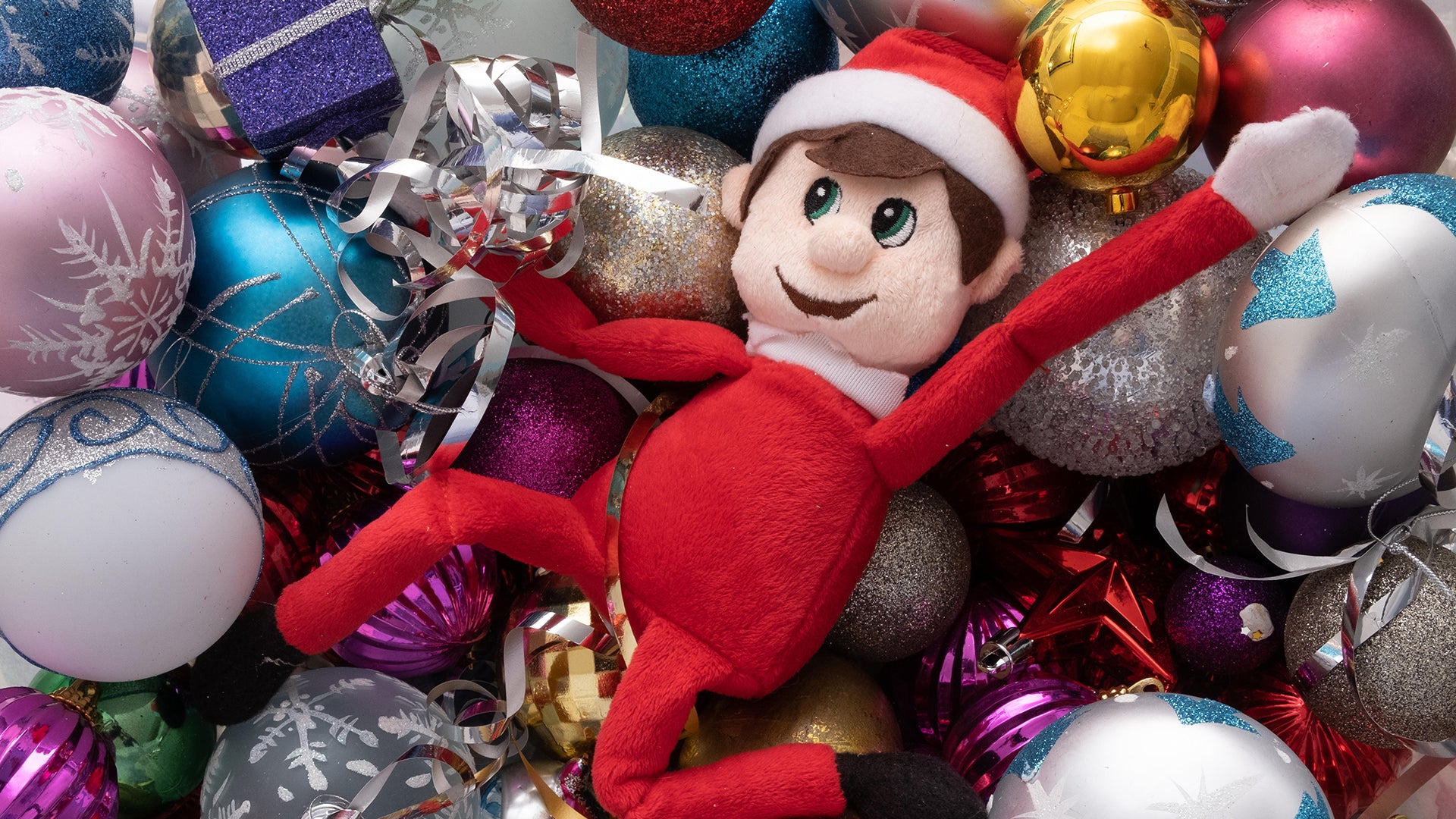 Elf on the shelf in a pile of baubles.